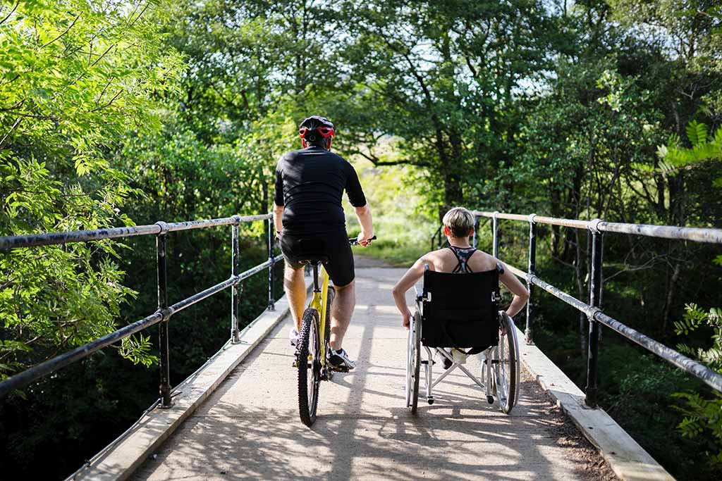 Cyclist and wheelchair user crossing bridge
