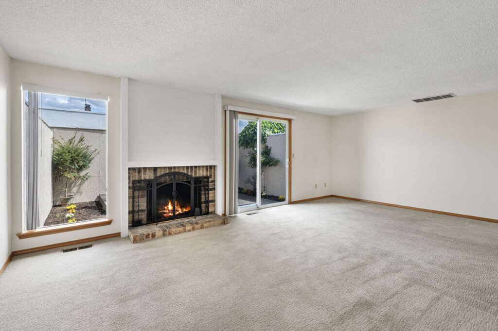 Spacious living room with wood burning fireplace and courtyard access