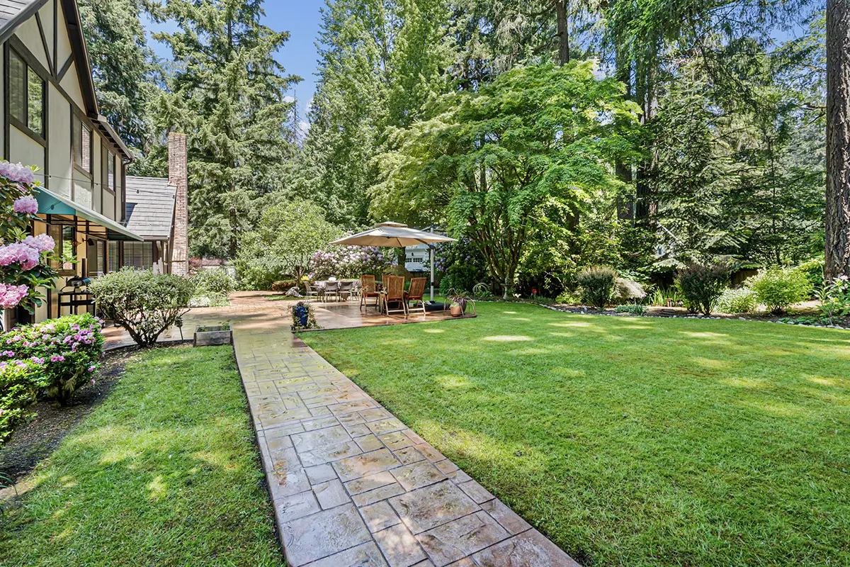 Concrete pathway connects patio to garage and utility shed